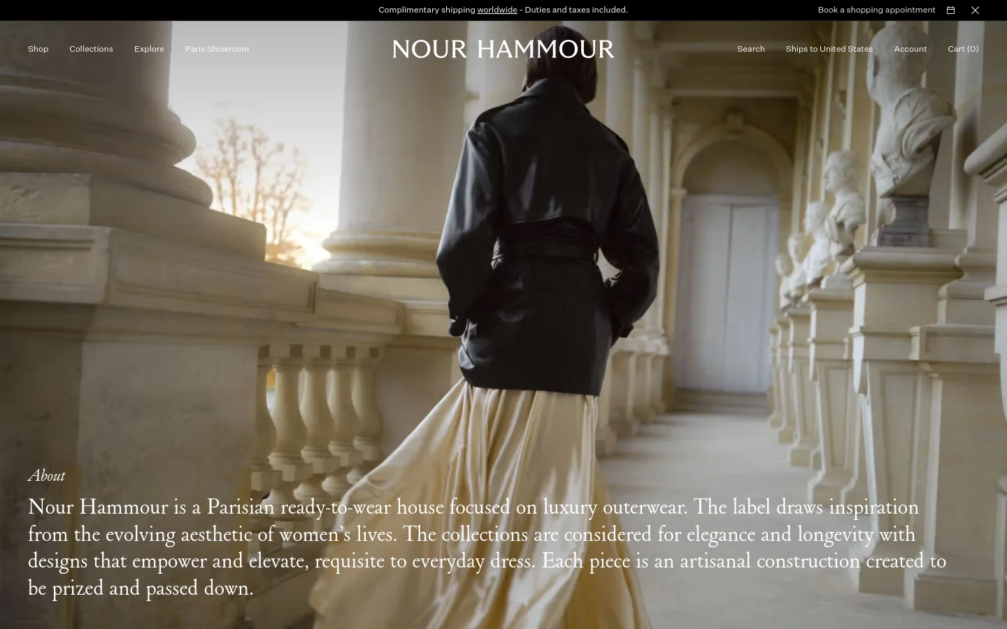 The desktop page features a large, cinematic hero image of a person in a black leather jacket and cream skirt walking through a classical Parisian colonnade. Overlaid on the bottom left is the heading 'About' and a paragraph describing Nour Hammour as a Parisian luxury outerwear house. The navigation menu is spread across the top with links for Shop, Collections, Explore, and Paris Showroom.
