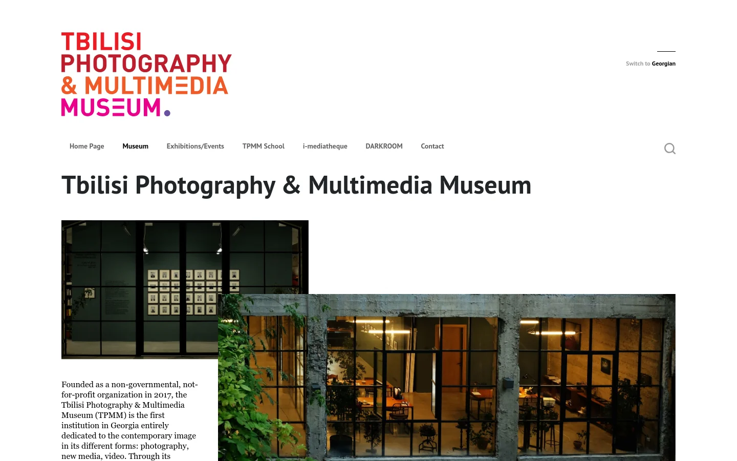 The desktop website features a clean white background with the large red and purple 'Tbilisi Photography & Multimedia Museum' logo at the top left. A horizontal navigation menu sits below the logo, followed by a large bold headline and a wide landscape photograph of a building interior with large glass windows. The layout is spacious with black text on a white background.
