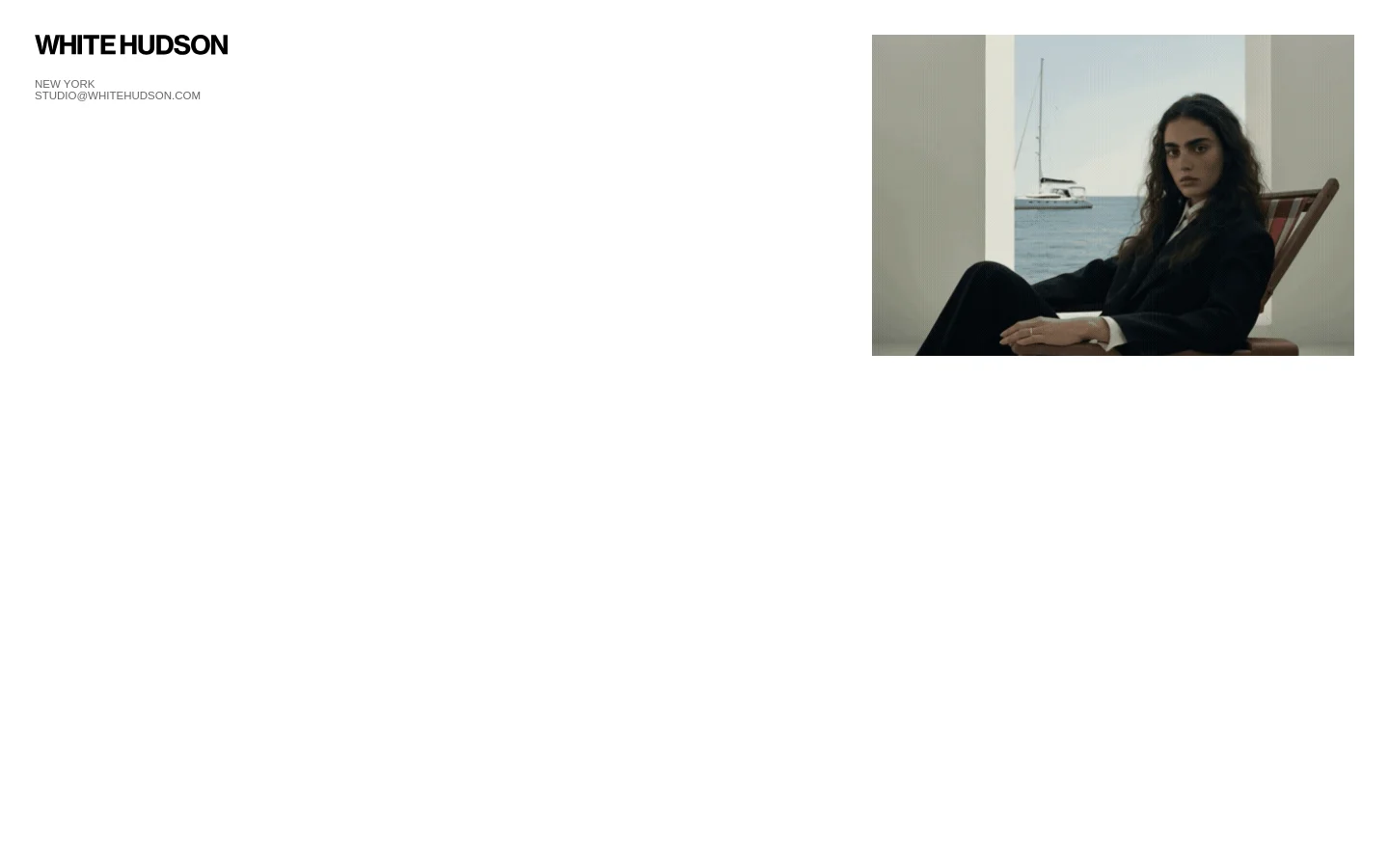 The desktop homepage features a minimalist white background with the brand name 'WHITE HUDSON' in bold black text on the left, accompanied by location and email details. On the right, a large rectangular photograph shows a woman in a dark suit sitting in a chair against a backdrop of a sailboat on the ocean.
