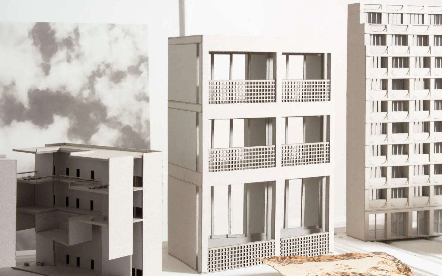 The desktop homepage features a large, high-resolution hero image of architectural scale models in a bright, minimalist studio setting. The layout includes a clean white background with the brand name 'JKLN' and a navigation menu containing links for 'Atelier de pratique et de recherche architecturale', 'Contact', 'Projets', and a language switcher. The color palette is neutral, dominated by whites, greys, and natural wood tones.