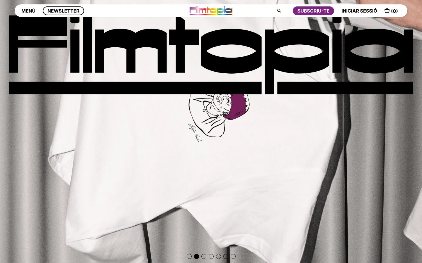 The desktop shop page features a large hero slider with bold 'Filmtopia' typography over images of merchandise like t-shirts and notebooks. Below the slider, a grid displays products such as gift cards and Agnès Varda themed items, each with a price and a 'COMPRAR' button. The layout uses a clean white background with a top navigation bar containing a menu, search icon, and user account links.