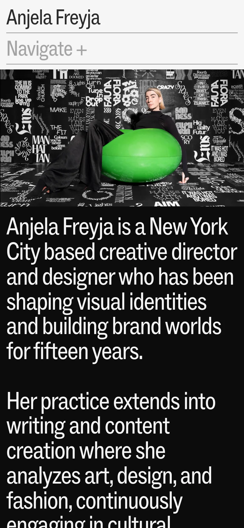 The mobile version presents a vertically stacked layout, starting with the name 'Anjela Freyja' and a 'Navigate +' expandable menu. Below the menu, the large hero image of the person and green sphere is displayed, followed by large-scale white text on a black background detailing the designer's professional background.