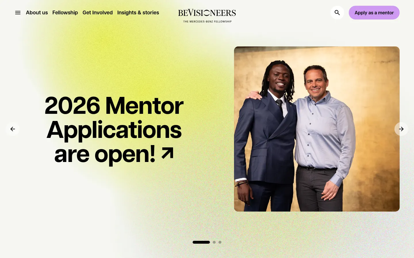 beVisioneers homepage featuring a split-screen hero section with large bold typography stating 2026 Mentor Applications are open. The layout pairs a lime green and off-white background with a high-quality portrait of two men, using a clean, modern editorial style.