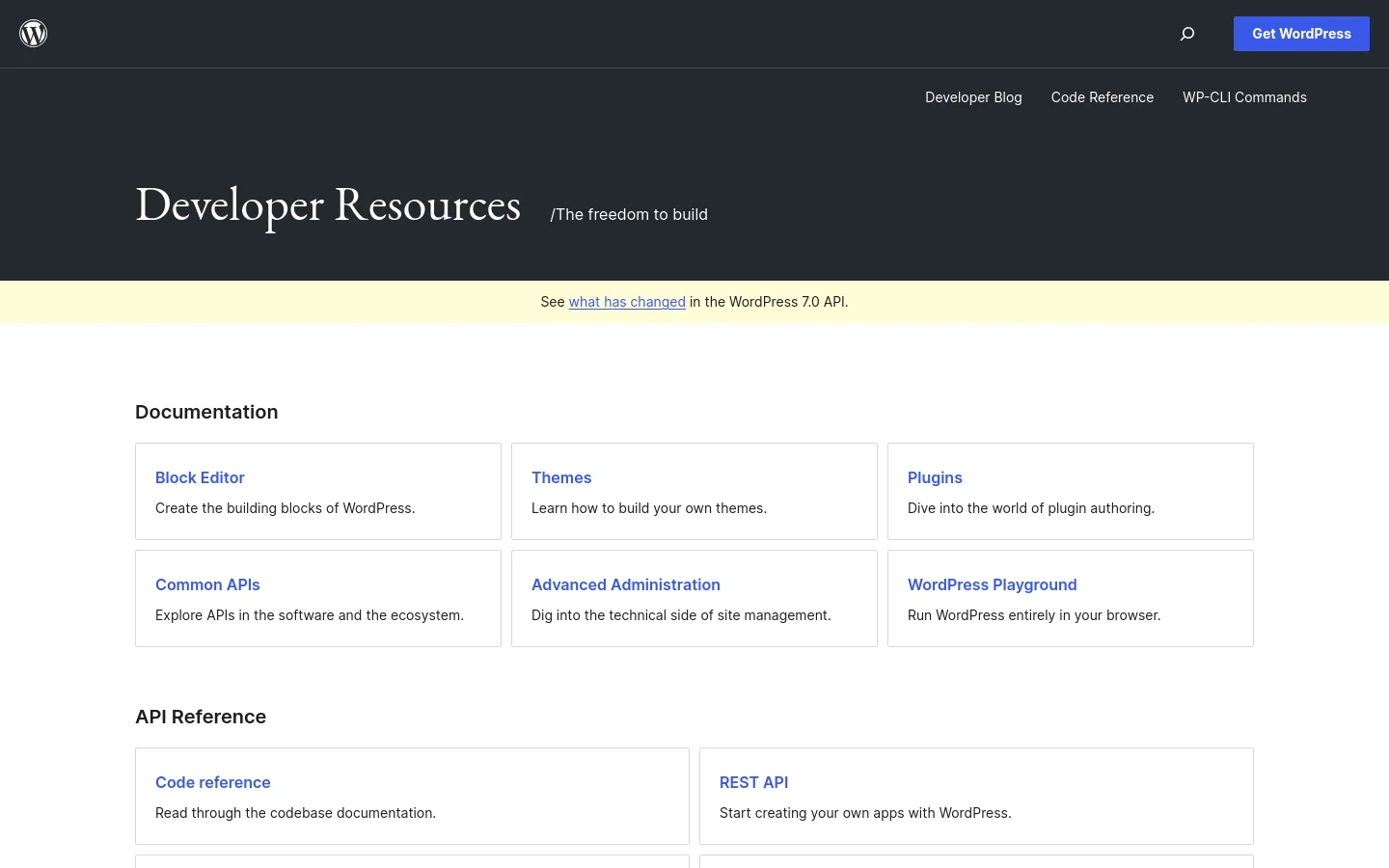 The WordPress Developer Resources homepage features a dark hero section with the large headline 'Developer Resources' and the tagline '/The freedom to build'. Below a light yellow notification bar, a white content area displays a grid of documentation cards for Block Editor, Themes, Plugins, and more, followed by an API Reference section. A top navigation bar includes links to the Developer Blog, Code Reference, and WP-CLI Commands.