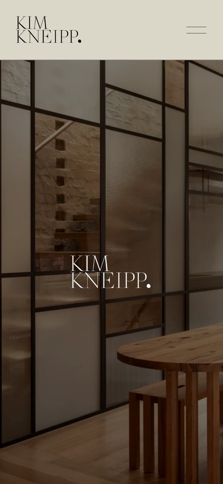 The mobile version presents a vertically oriented hero image of a glass-paneled interior, with the 'KIM KNEIPP.' logo centered in white serif text. The top navigation is simplified into a hamburger menu icon on the right, and the overall aesthetic maintains the minimalist, neutral-toned design of the desktop site.