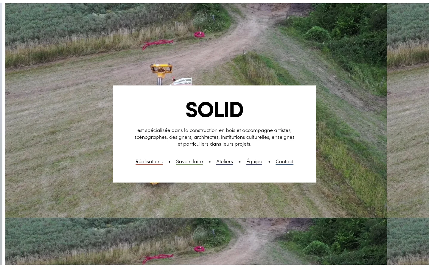 The desktop homepage features a large background image of a grassy field with a dirt path. A central white box contains the bold headline 'SOLID', a description of their wood construction services, and a horizontal navigation menu with links like Réalisations and Savoir-faire.