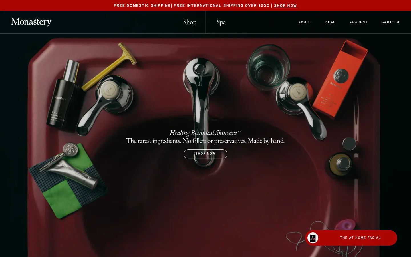 The desktop homepage features a dark, elegant aesthetic with a large hero image of a deep red sink surrounded by botanical skincare products and grooming tools. Centered text reads 'Healing Botanical Skincare™' above a 'SHOP NOW' button, with a navigation bar at the top containing links for Shop, Spa, About, and Read. A red promotional banner at the very top offers free shipping information.