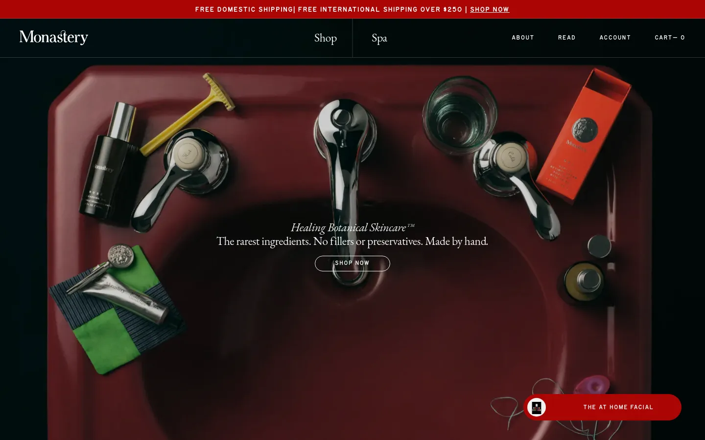 The desktop homepage features a dark, elegant aesthetic with a large hero image of a deep red sink surrounded by botanical skincare products and grooming tools. Centered text reads 'Healing Botanical Skincare™' above a 'SHOP NOW' button, with a navigation bar at the top containing links for Shop, Spa, About, and Read. A red promotional banner at the very top offers free shipping information.
