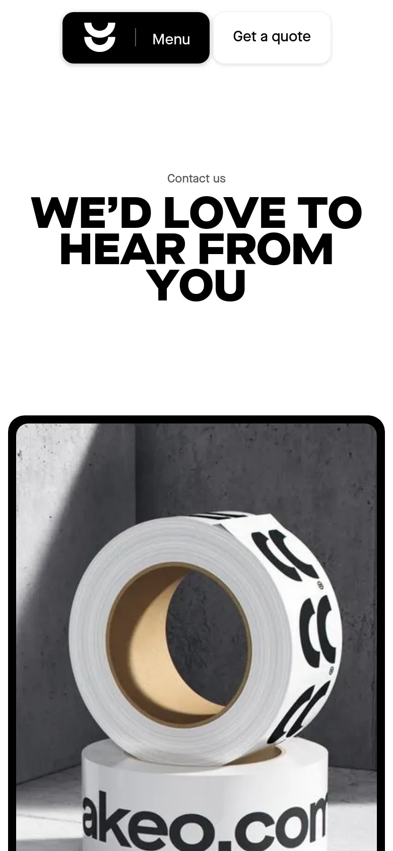 The mobile version presents a simplified vertical layout with a condensed header containing the logo, a 'Menu' button, and a 'Get a quote' button. The large, bold headline 'WE’D LOVE TO HEAR FROM YOU' is centered above a full-width grayscale image of a roll of tape with 'akeo.com' printed on it.