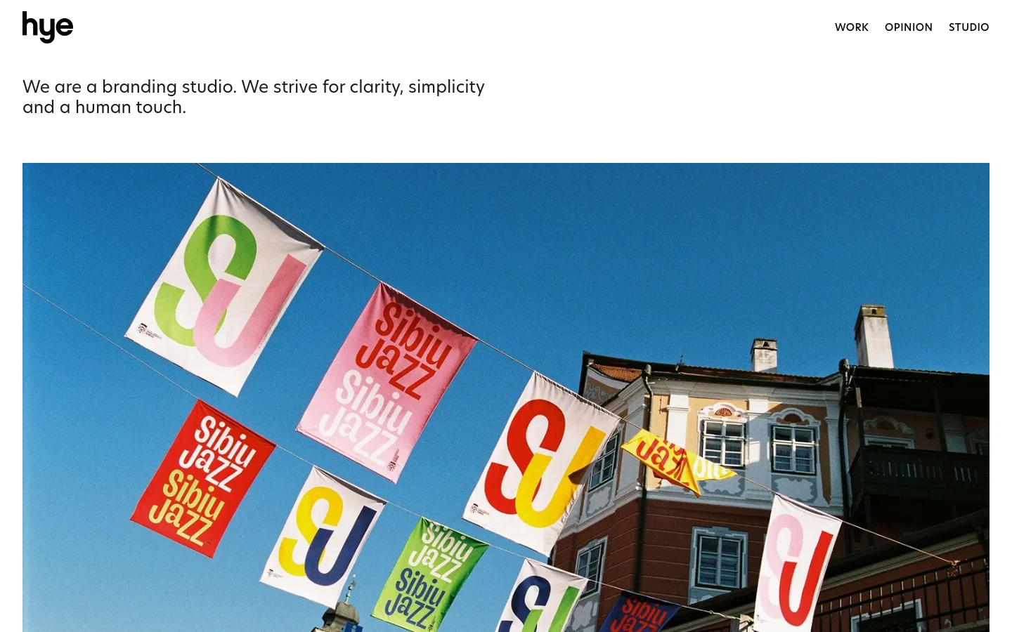 The desktop homepage features a minimalist white background with black text and a navigation menu including Work, Opinion, and Studio. A large hero image shows colorful Sibiu Jazz flags hanging against a blue sky in front of a building, followed by a section showcasing rebranding projects like Sibiu Jazz and Omniscope.