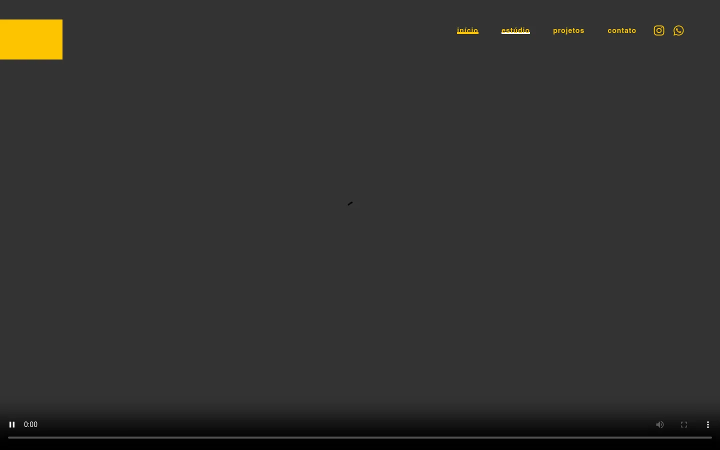 A minimalist dark gray webpage for Ber Sardi's Estúdio featuring a large video player occupying most of the screen. The top navigation bar includes links for 'início', 'estúdio', 'projetos', and 'contato', alongside Instagram and WhatsApp icons, set against a dark background with a yellow accent block in the top left.