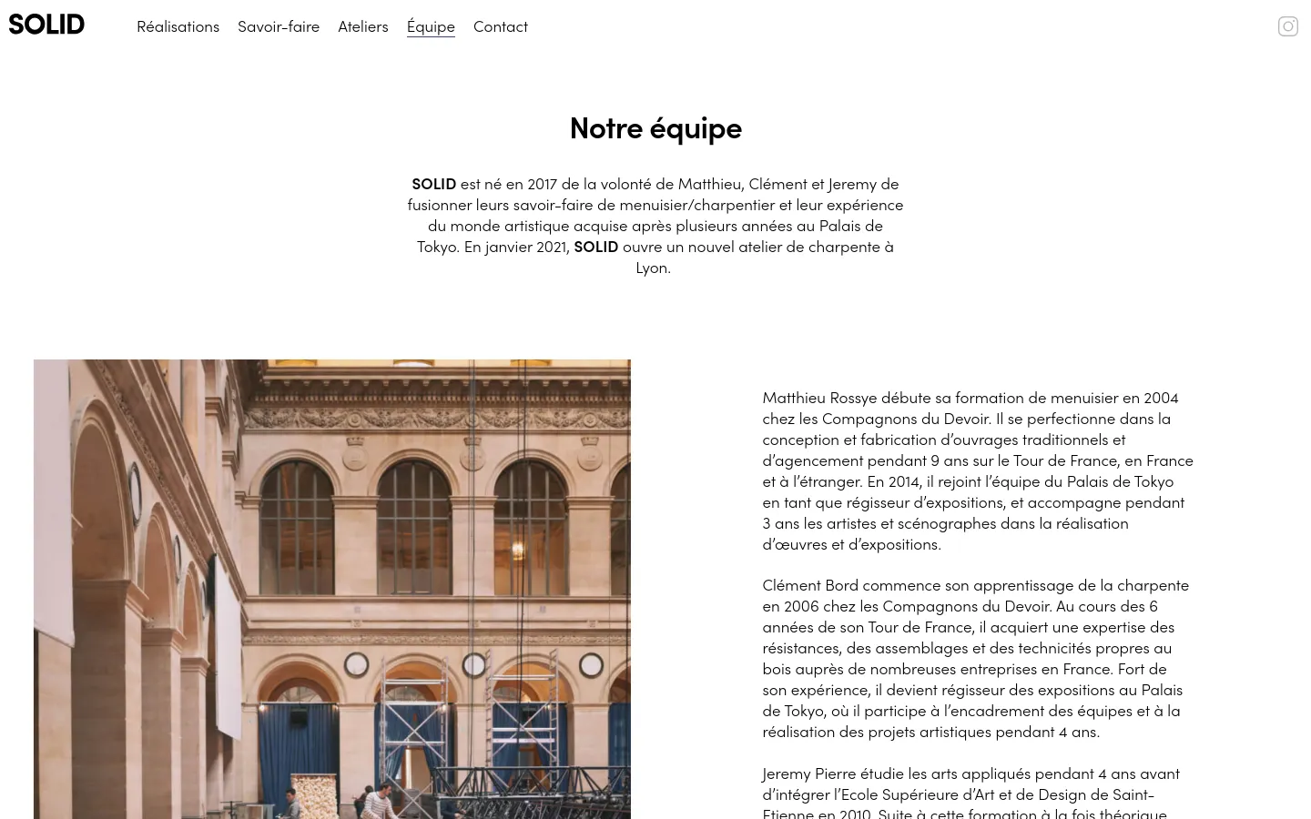 The desktop page features a clean, white layout with a top navigation menu and the headline 'Notre équipe'. Below the introductory text, a large photograph shows a woodworking installation being set up inside a grand, classical building with high arches and stone columns.