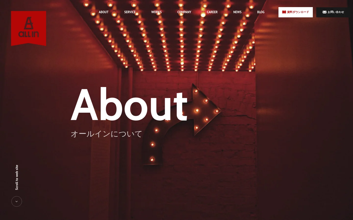The desktop About page features a dark red hero section with a marquee light background and large white 'About' text. A navigation menu at the top includes links for About, Service, Works, Company, Career, News, and Blog, alongside red 'Download' and white 'Contact' buttons. The layout is spacious with a vertical 'Scroll to web site' indicator on the left.