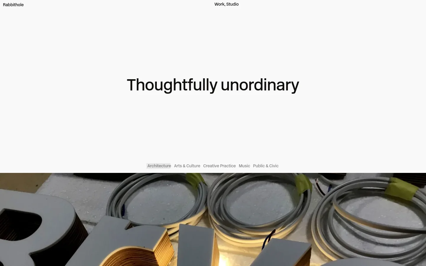 The desktop homepage features a minimalist white background with the large headline 'Thoughtfully unordinary' centered in the upper half. Below the headline, a horizontal navigation menu lists industry categories like Architecture and Arts & Culture. A large, wide-format hero image showing coiled cables sits at the bottom of the viewport.