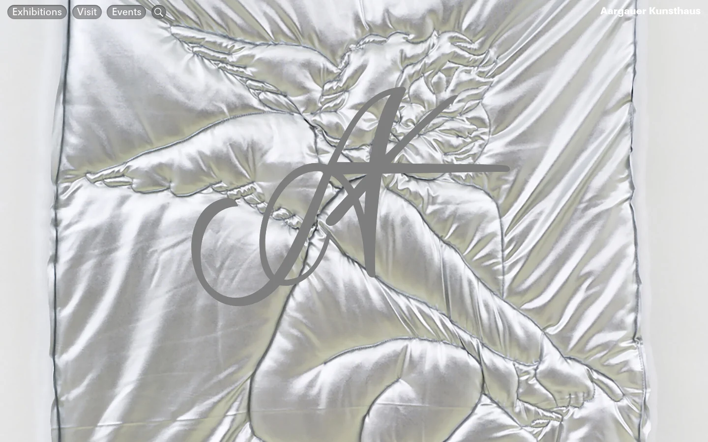 The desktop homepage features a large, full-screen hero image of a silver, satin-like fabric with a quilted cherub figure and a large 'AK' monogram overlay. A minimalist navigation bar at the top left includes links for 'Exhibitions', 'Visit', and 'Events' alongside a search icon, with the museum name 'Aargauer Kunsthaus' in the top right.