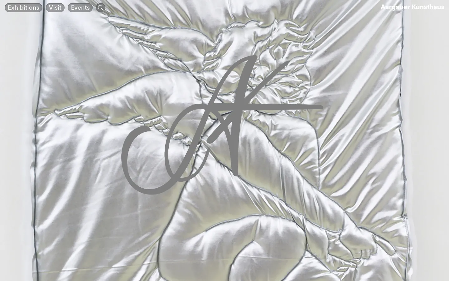 The desktop homepage features a large, full-screen hero image of a silver, satin-like fabric with a quilted cherub figure and a large 'AK' monogram overlay. A minimalist navigation bar at the top left includes links for 'Exhibitions', 'Visit', and 'Events' alongside a search icon, with the museum name 'Aargauer Kunsthaus' in the top right.