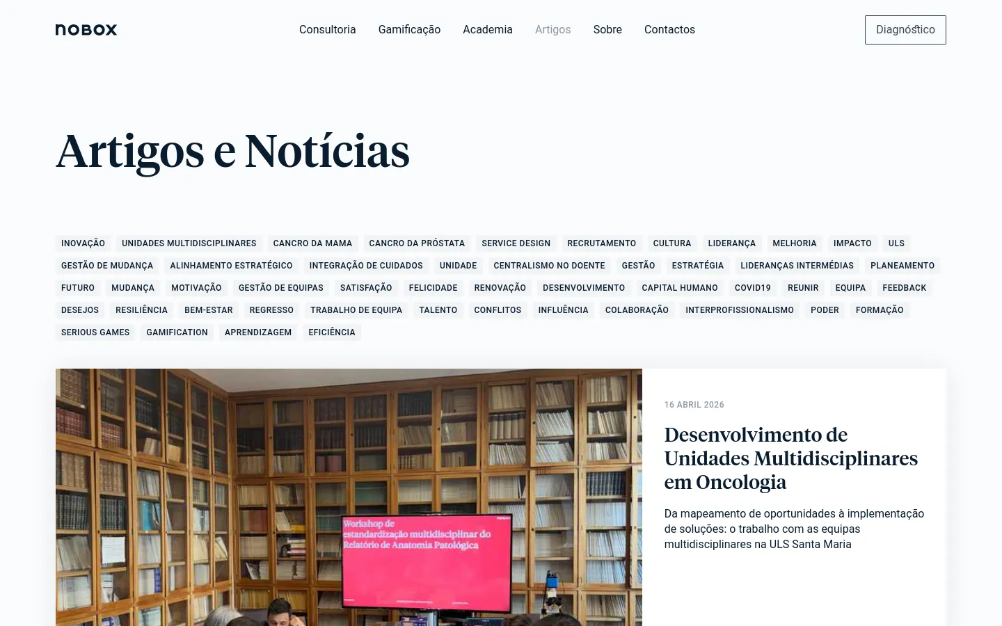 The desktop version of the Artigos e Notícias page features a clean, white background with a large black headline. Below the headline, a dense grid of clickable text tags covers various topics like innovation and leadership, followed by a featured article section containing a large photograph of a workshop and a text summary on the right. The navigation menu is visible at the top with links for Consultoria, Gamificação, Academia, Artigos, Sobre, and Contactos, alongside a 'Diagnóstico' button.