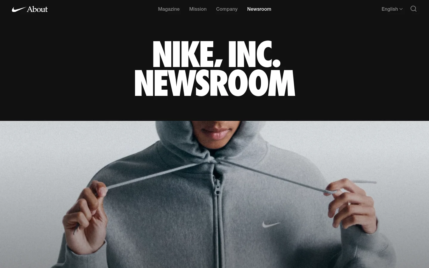 The Nike, Inc. Newsroom homepage features a minimalist black header with navigation links for Magazine, Mission, Company, and Newsroom. A large hero section displays the bold white text 'NIKE, INC. NEWSROOM' against a black background, followed by a large image of a person wearing a grey Nike Studio Fleece hoodie. Below the hero, news articles are presented with large imagery and headlines.