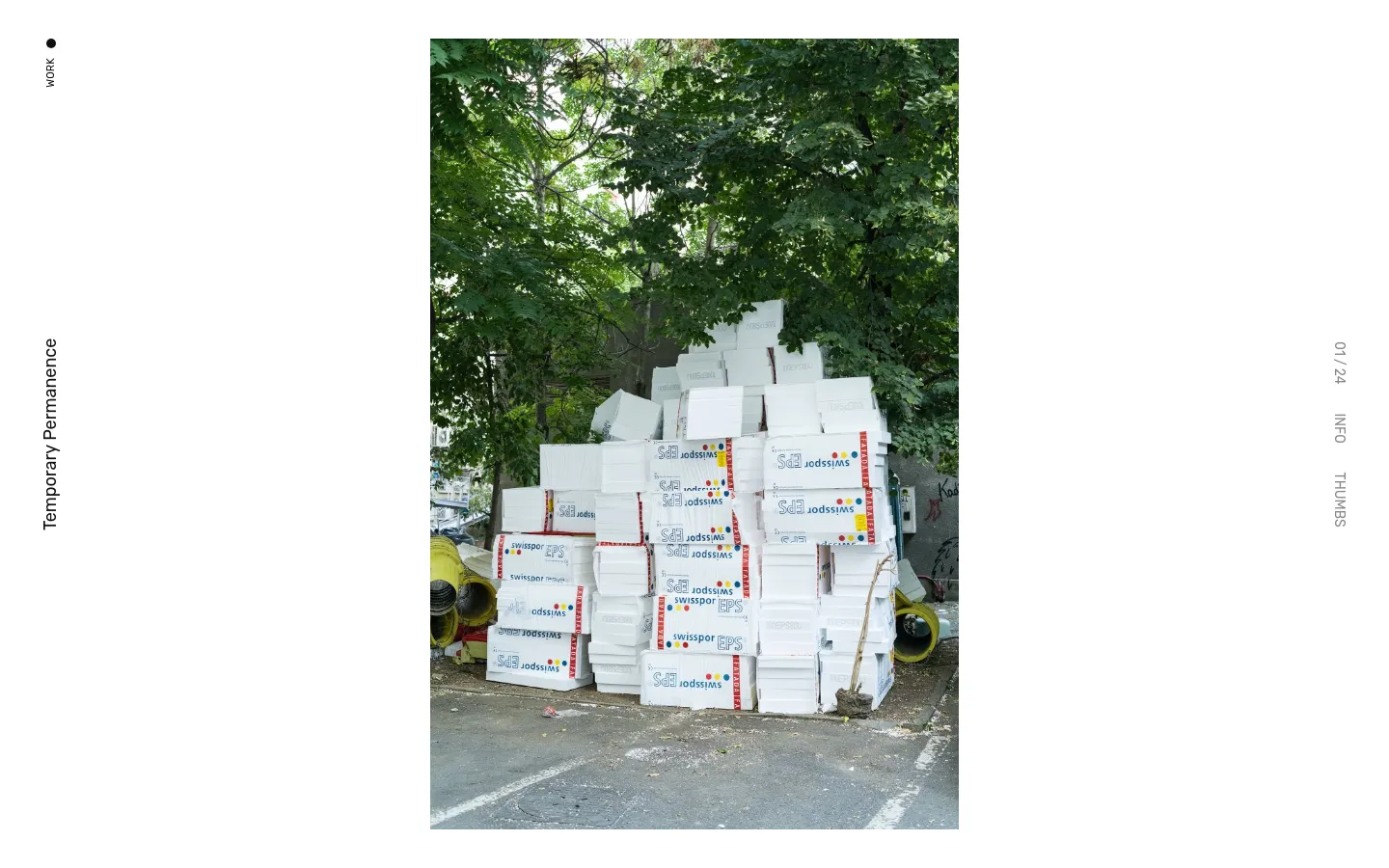 The desktop version features a minimalist white layout with vertical navigation text on the left and right margins. A large, vertical portrait photograph of stacked white Styrofoam boxes under green trees dominates the center, with the title 'Temporary Permanence' appearing in the sidebar.