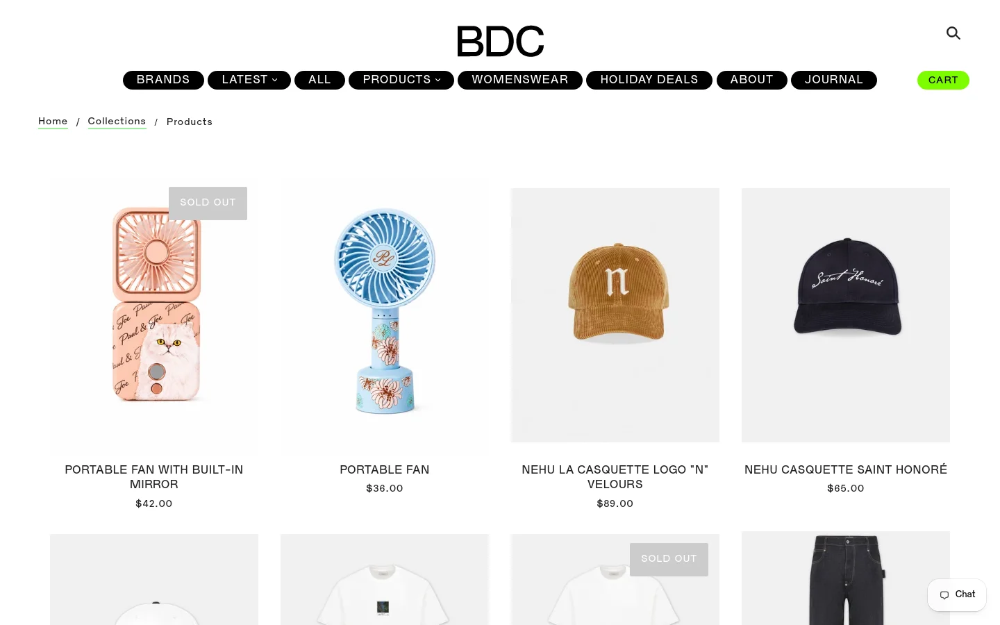 The desktop website displays a minimalist white product grid for the 'All' collection, featuring items like portable fans and caps with prices listed below each image. A black navigation bar at the top includes links for Brands, Latest, All, Products, Womenswear, Holiday Deals, About, and Journal, alongside a search icon and a bright green 'CART' button. The layout is spacious with a clean, high-fashion aesthetic.