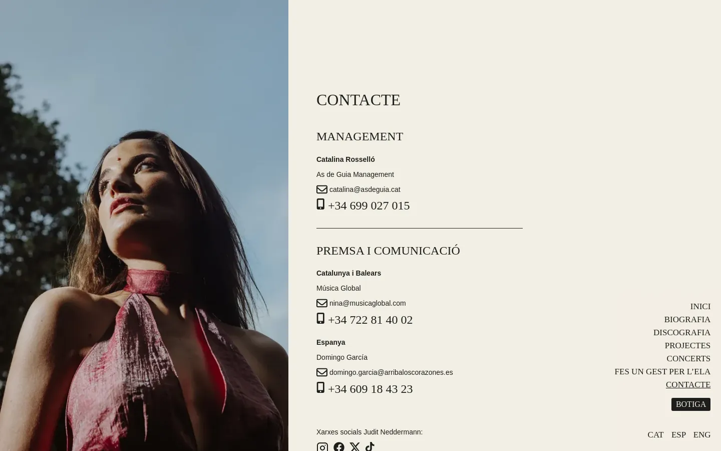 The desktop page features a large vertical portrait of a woman on the left side against a blue sky background. On the right, a cream-colored column contains contact information for management and press, organized with headings, names, email addresses, and phone numbers, followed by social media icons at the bottom.