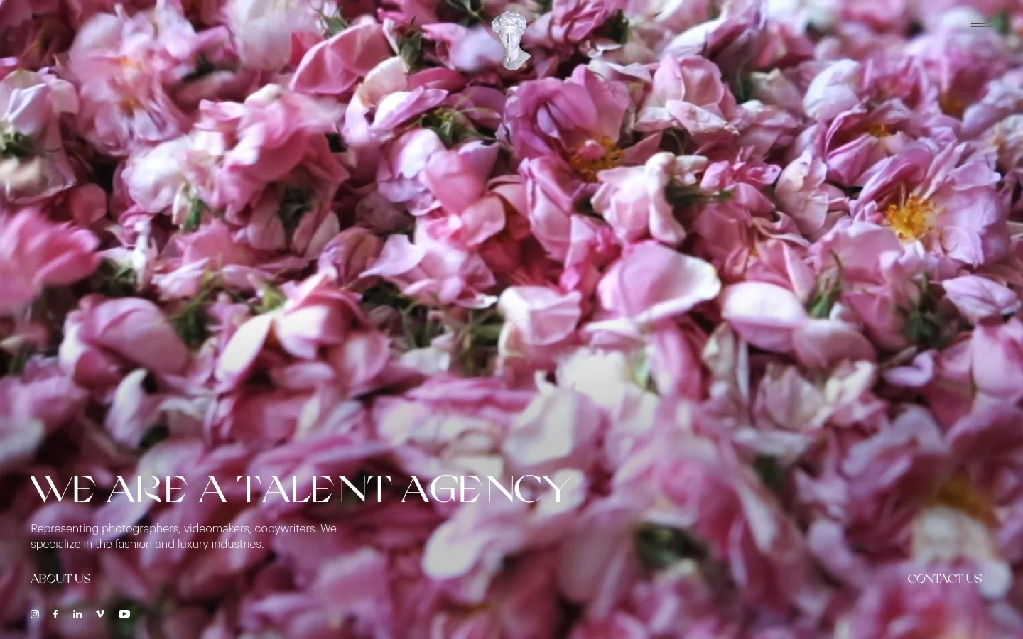 The desktop homepage features a full-screen, high-resolution hero image of dense pink rose petals. Centered white text reads 'WE ARE A TALENT AGENCY' followed by a brief description, with 'ABOUT US' and 'CONTACT US' links positioned at the bottom corners and social media icons in the bottom left.