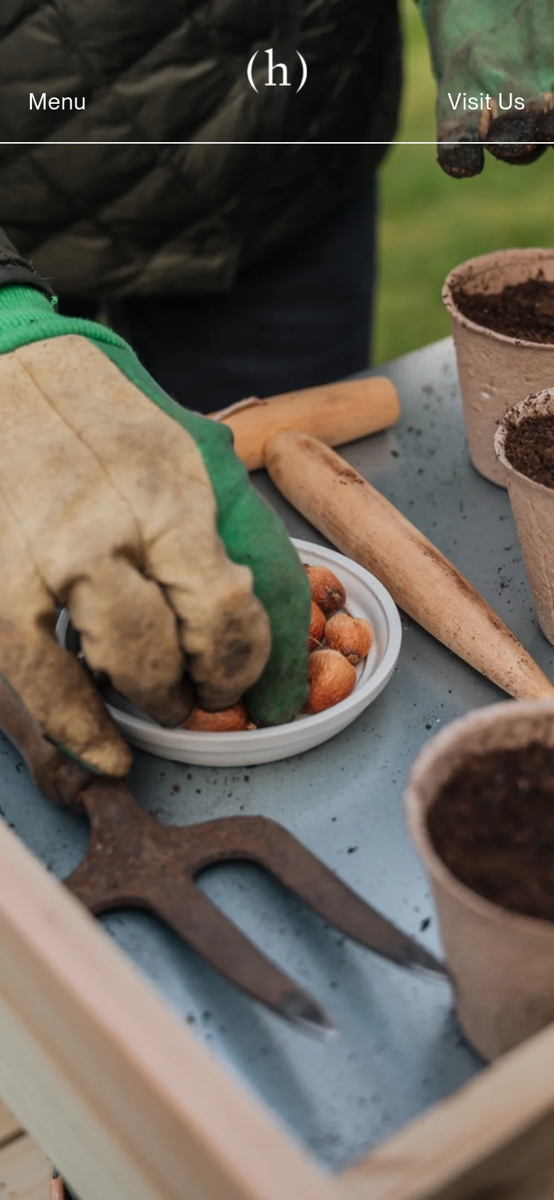 The mobile version maintains the same garden-themed hero image but uses a simplified layout with 'Menu' and 'Visit Us' text links positioned at the top corners. The imagery is tightly cropped to focus on the hands, gardening tools, and seed pots.