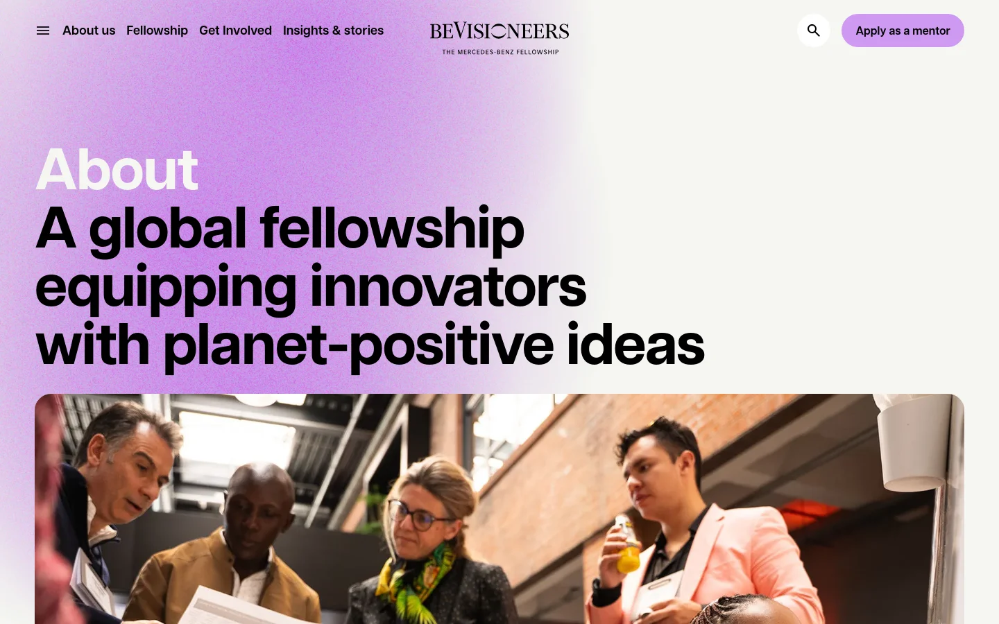 BeVisioneers About us page featuring a large hero headline, A global fellowship equipping innovators with planet-positive ideas, set against a soft purple gradient background. The layout uses bold sans-serif typography above a wide photograph of diverse people collaborating in a bright, modern indoor space.