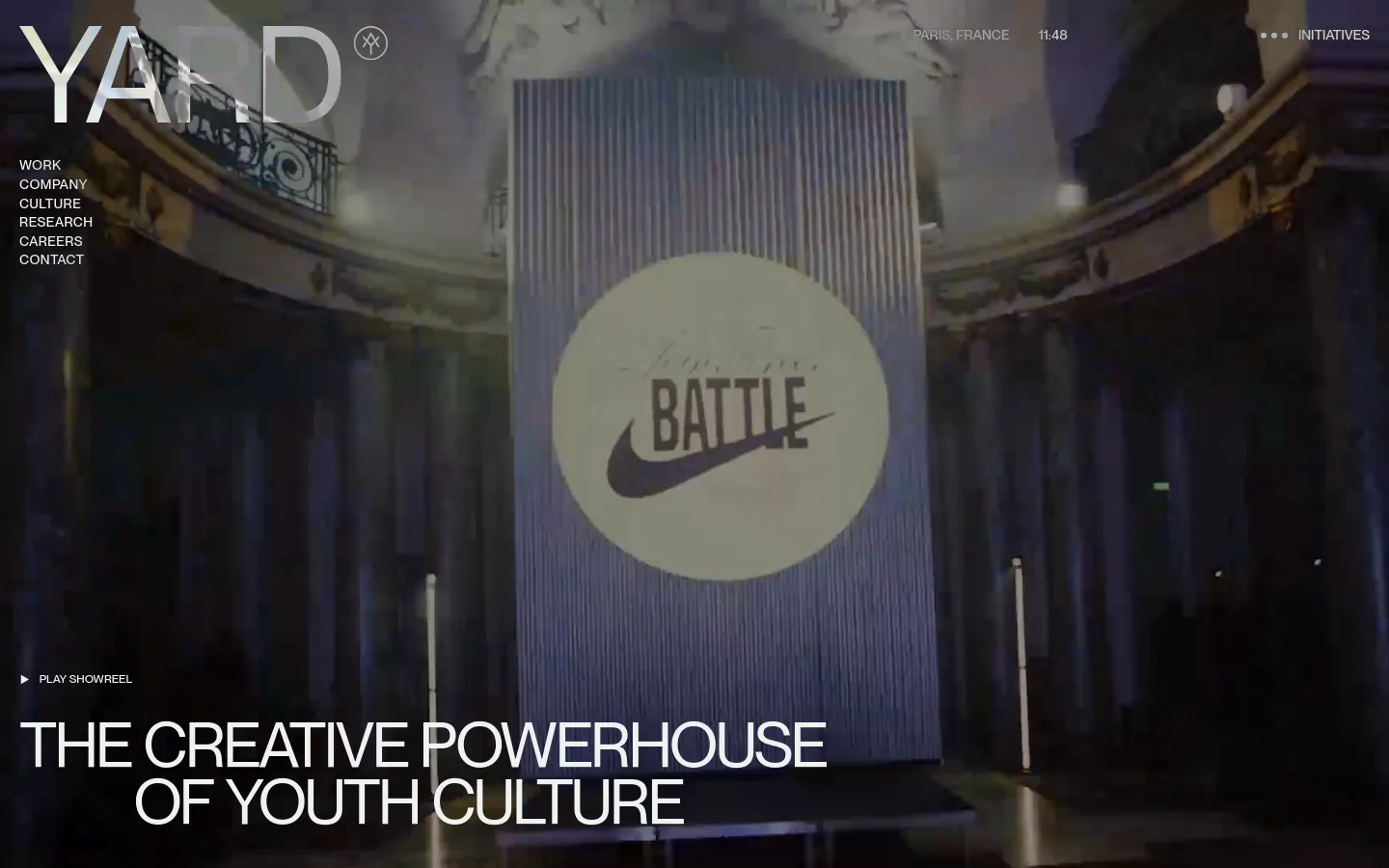 The desktop homepage features a large, cinematic background video showing a Nike-branded structure under dim lighting. The YARD logo is prominent in the top left, with a navigation menu on the left and a 'Play Showreel' call to action above the large headline, 'THE CREATIVE POWERHOUSE OF YOUTH CULTURE'.