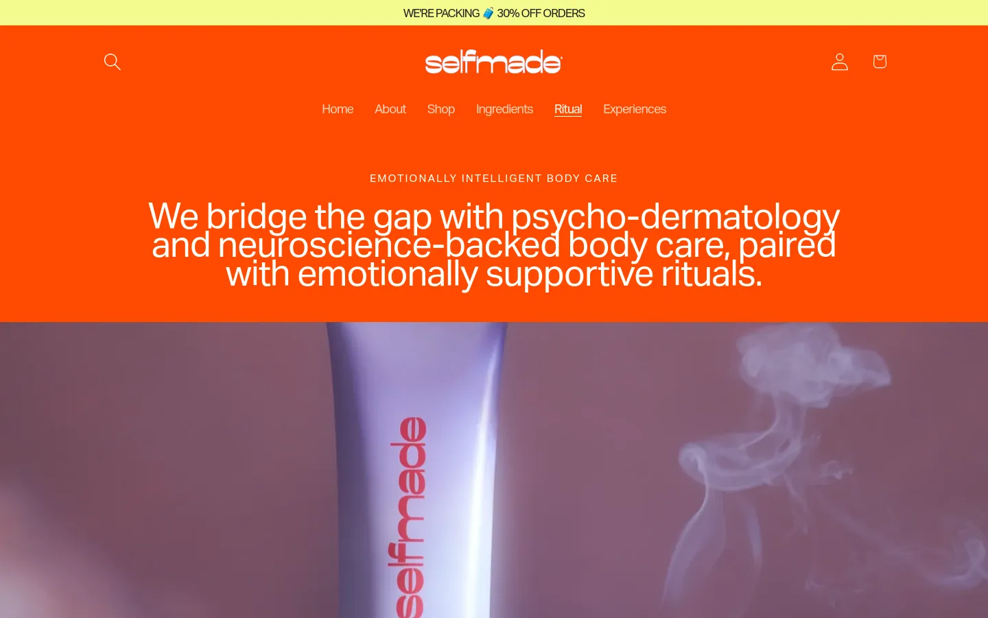 The desktop page features a vibrant orange header with a white logo, navigation links, and a search icon. A large hero section displays white text over an orange background, followed by a high-resolution close-up image of a lavender-colored product tube amidst soft smoke. The layout is spacious and centered, emphasizing the headline about psycho-dermatology.