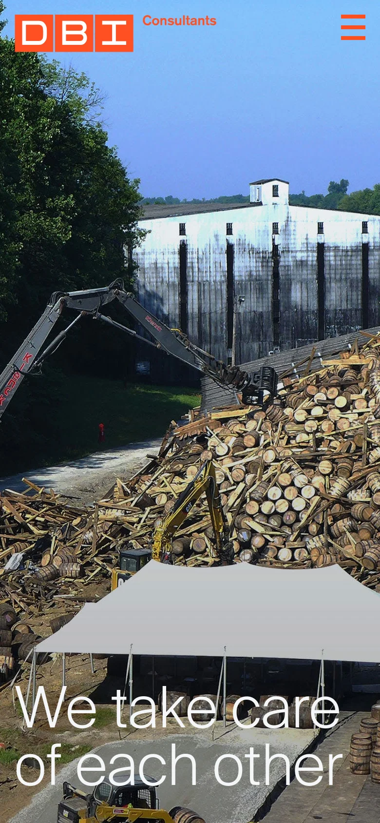 The mobile version shows a vertically cropped version of the hero image, focusing on the construction machinery and the pile of logs. The headline changes to 'We take care of each other' and is positioned in the lower half of the screen. The navigation is condensed into a hamburger menu in the top right, and the orange 'Submit Assignment' button is not visible in the header.