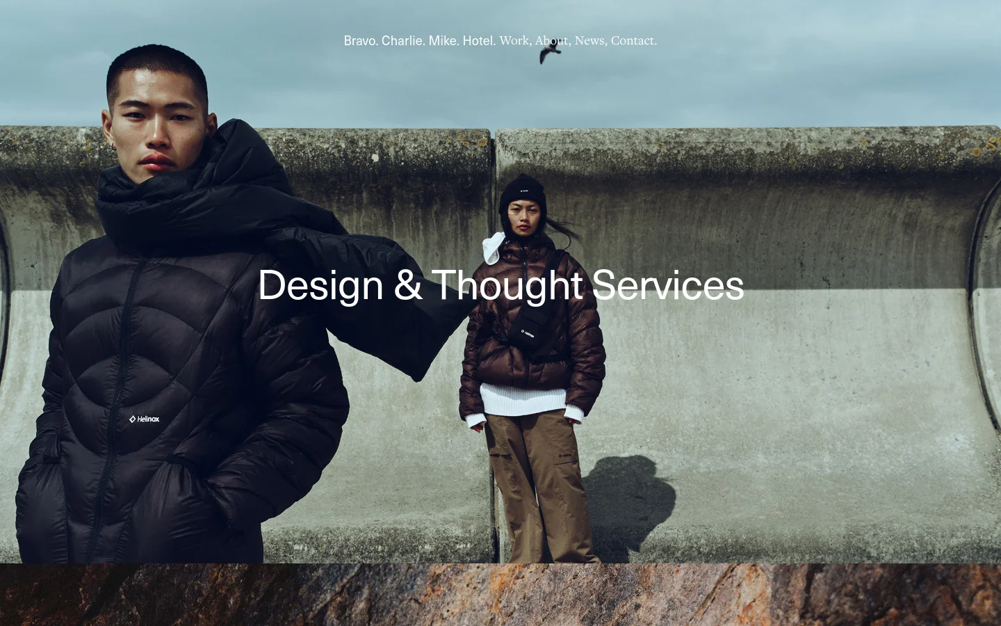 The desktop homepage features a minimalist design with a large hero image of two people in winter clothing against a concrete wall and cloudy sky. The agency name 'Bravo. Charlie. Mike. Hotel.' and navigation links like Work, About, News, and Contact are displayed in white text at the top, with the headline 'Design & Thought Services' centered over the image.