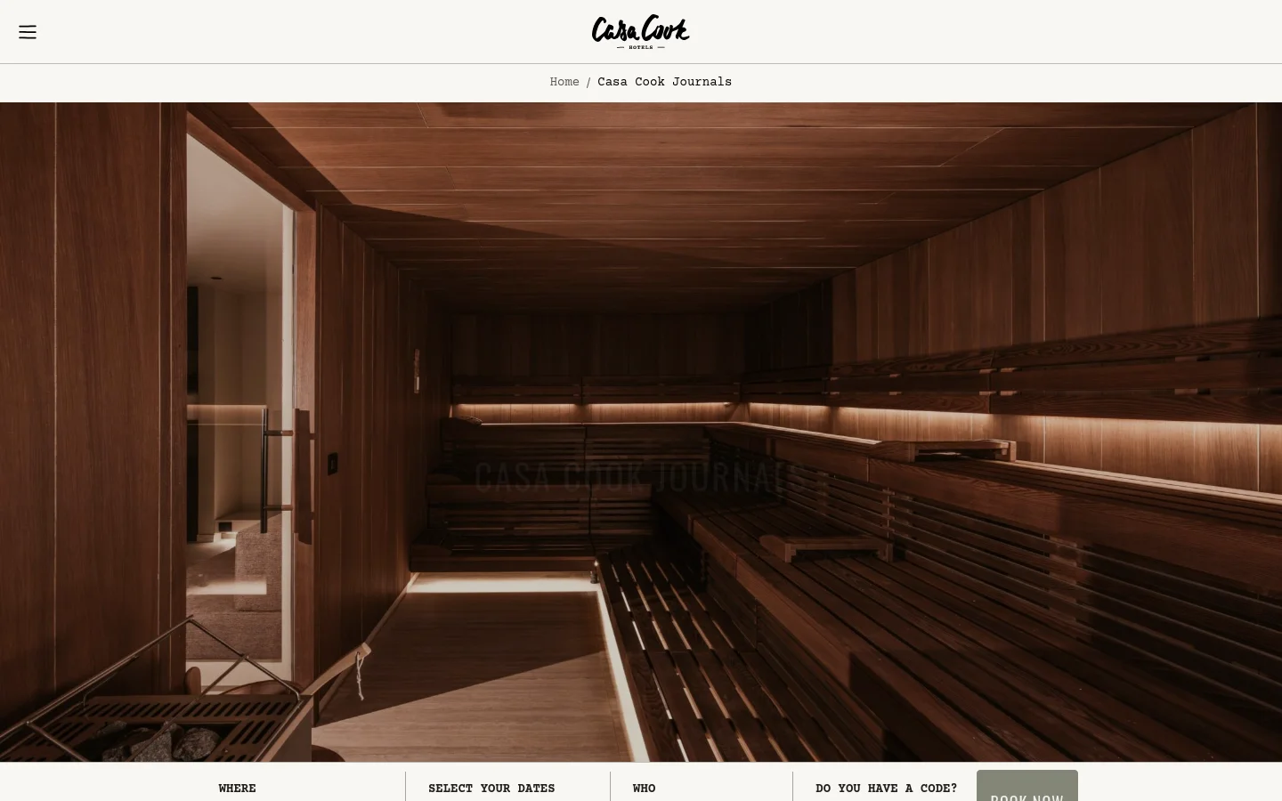 The Casa Cook Journals blog landing page features a large hero image of a warm, wood-paneled sauna with soft ambient lighting. The headline 'CASA COOK JOURNALS' is centered in white capital letters over the image, with a 'BOOK YOUR STAY' call to action bar at the bottom. The layout is clean and minimalist with a white navigation bar at the top containing the brand logo.