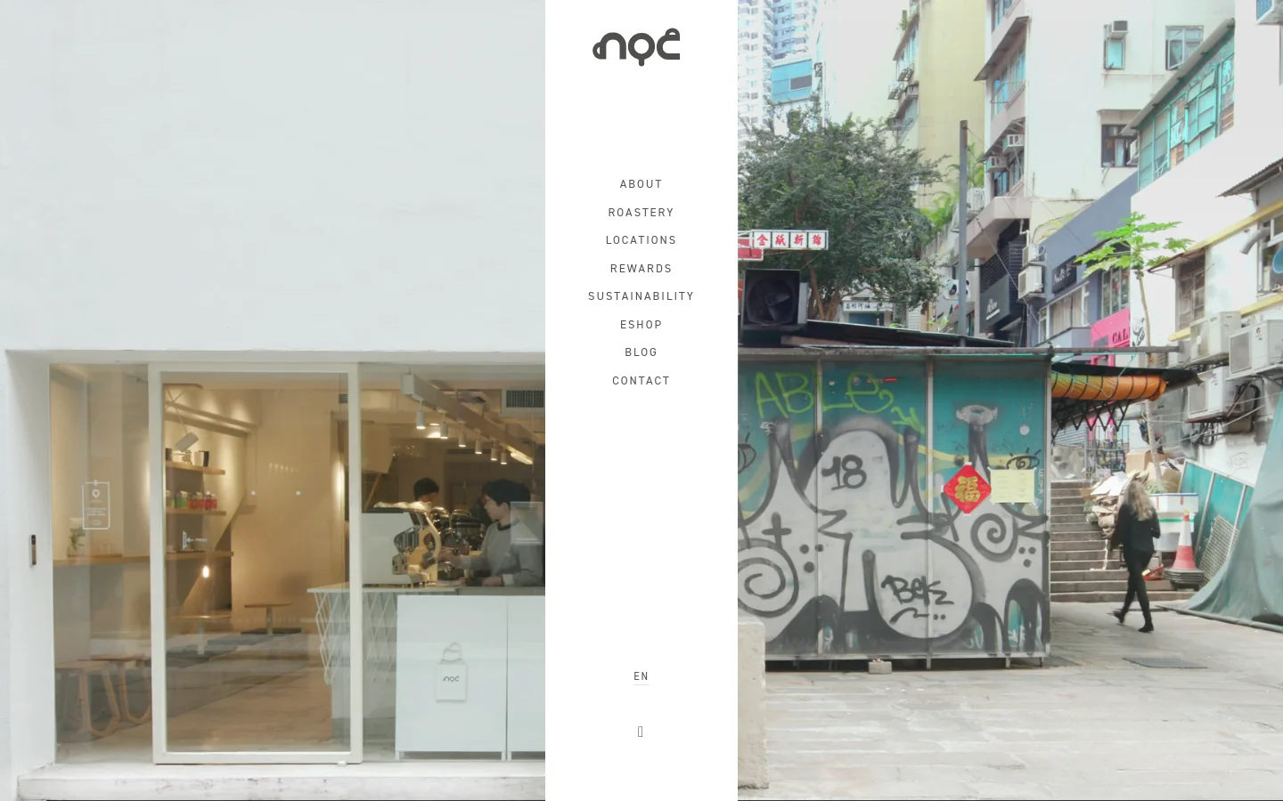 The desktop homepage features a minimalist design with a large, high-quality hero image of a modern cafe interior seen through a glass window. A clean white vertical sidebar on the left contains the NOC logo, a navigation menu with links like About and Roastery, and a language selector. The overall aesthetic is bright, airy, and sophisticated with a neutral color palette.