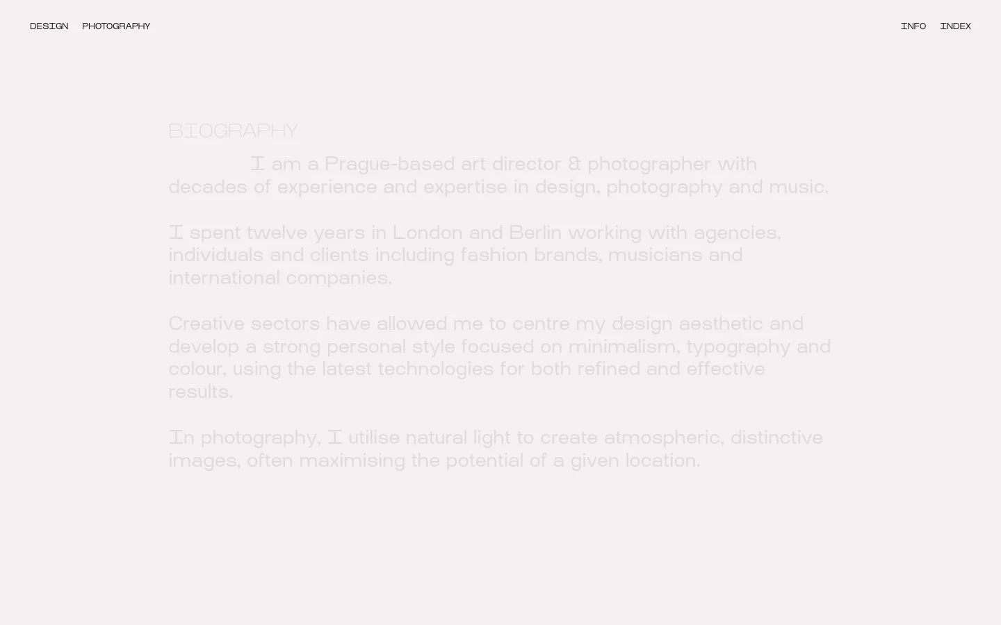 A minimalist desktop webpage with a light grey background and dark grey text. The layout features a top navigation bar with links for Design, Photography, Info, and Index, followed by a large 'BIOGRAPHY' heading and several paragraphs of text. The content is organized with ample white space and clean typography.