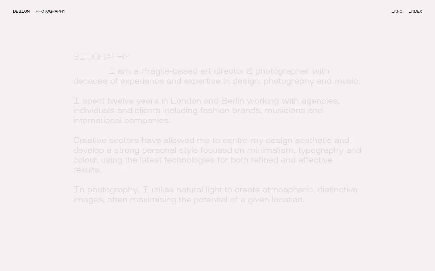 A minimalist desktop webpage with a light grey background and dark grey text. The layout features a top navigation bar with links for Design, Photography, Info, and Index, followed by a large 'BIOGRAPHY' heading and several paragraphs of text. The content is organized with ample white space and clean typography.
