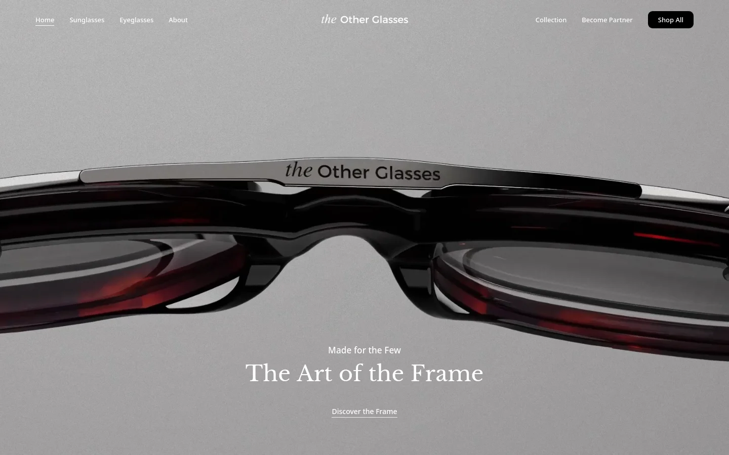 The desktop homepage features a minimalist, high-end design with a large hero image of luxury eyewear against a light gray background. The navigation bar includes links for Sunglasses, Eyeglasses, and About, alongside a 'Shop All' call to action button. Centered text reads 'Made for the Few' and 'The Art of the Frame' above a 'Discover the Frame' link.