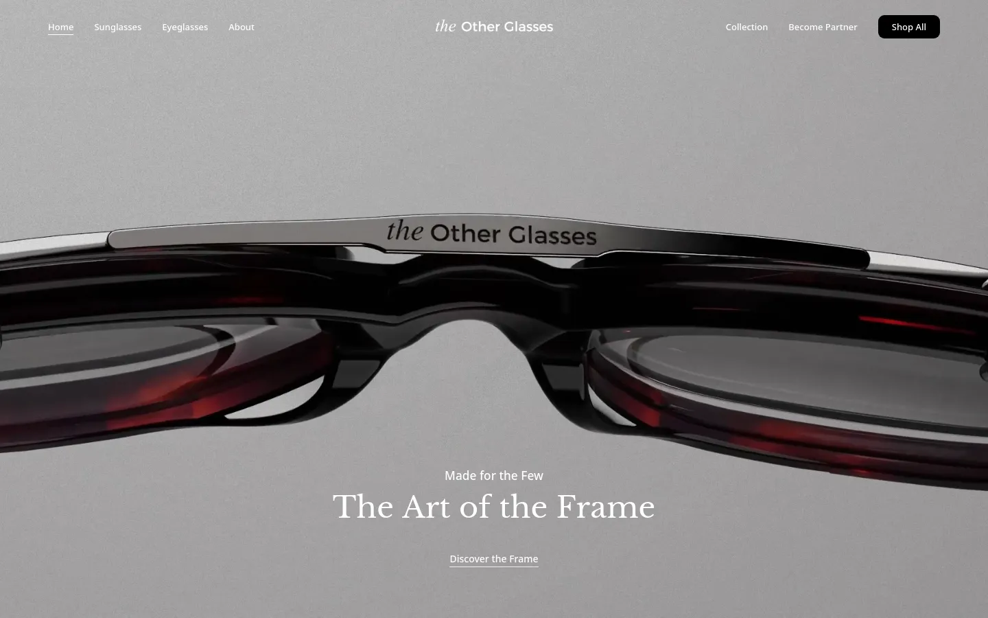 The desktop homepage features a minimalist, high-end design with a large hero image of luxury eyewear against a light gray background. The navigation bar includes links for Sunglasses, Eyeglasses, and About, alongside a 'Shop All' call to action button. Centered text reads 'Made for the Few' and 'The Art of the Frame' above a 'Discover the Frame' link.