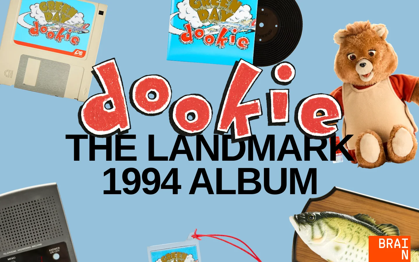 The desktop homepage features a light blue background with a collage of eclectic objects including a floppy disk, a teddy bear, a fish mount, and an answering machine. Large, stylized red and white text reads 'dookie THE LANDMARK 1994 ALBUM' centered in the hero section.