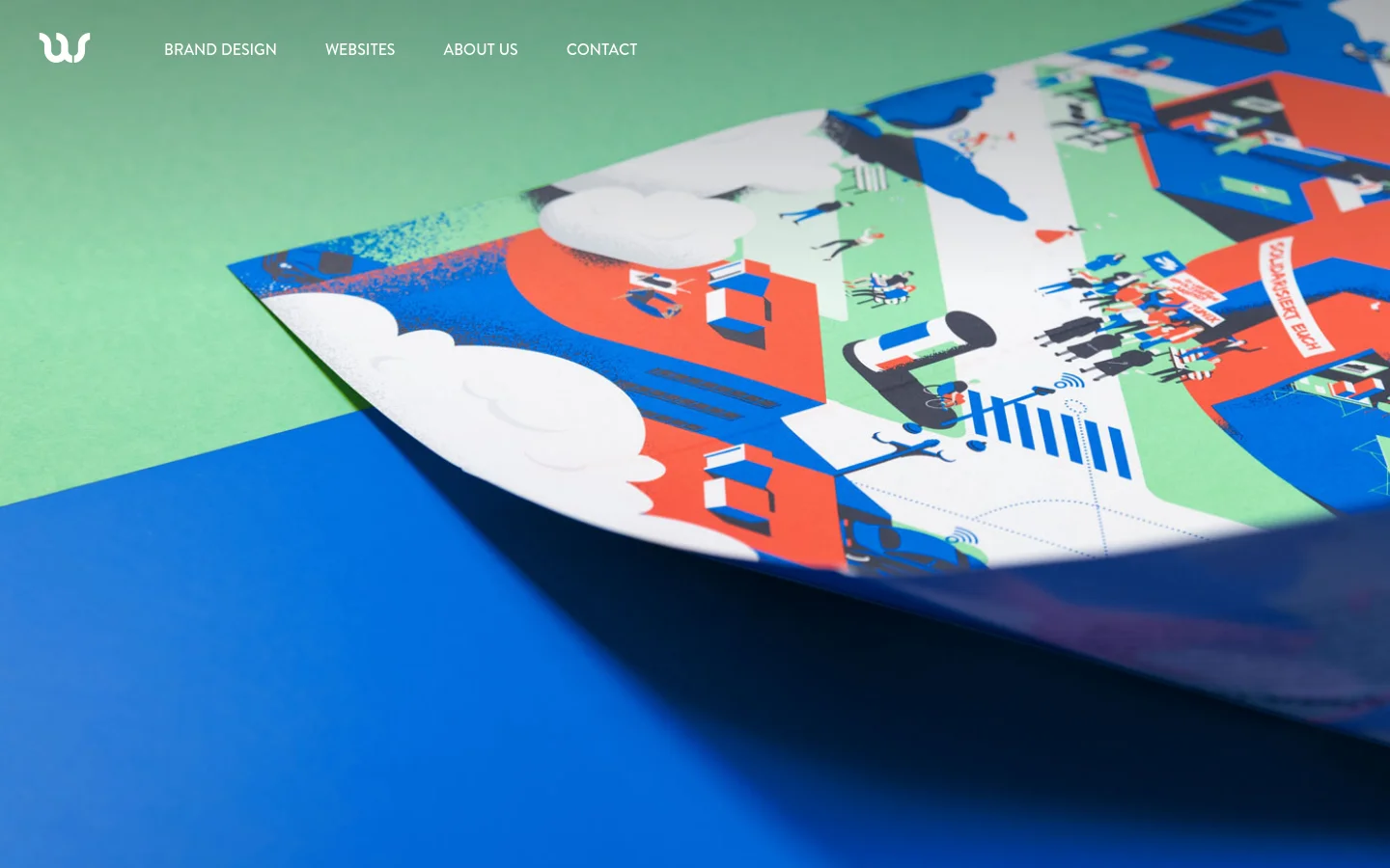The desktop homepage features a minimalist navigation bar at the top with the 'us' logo and links for Brand Design, Websites, About Us, and Contact. The hero section displays a large, vibrant close-up photograph of a colorful, illustrated print with red, blue, and white elements resting on a green and blue background.