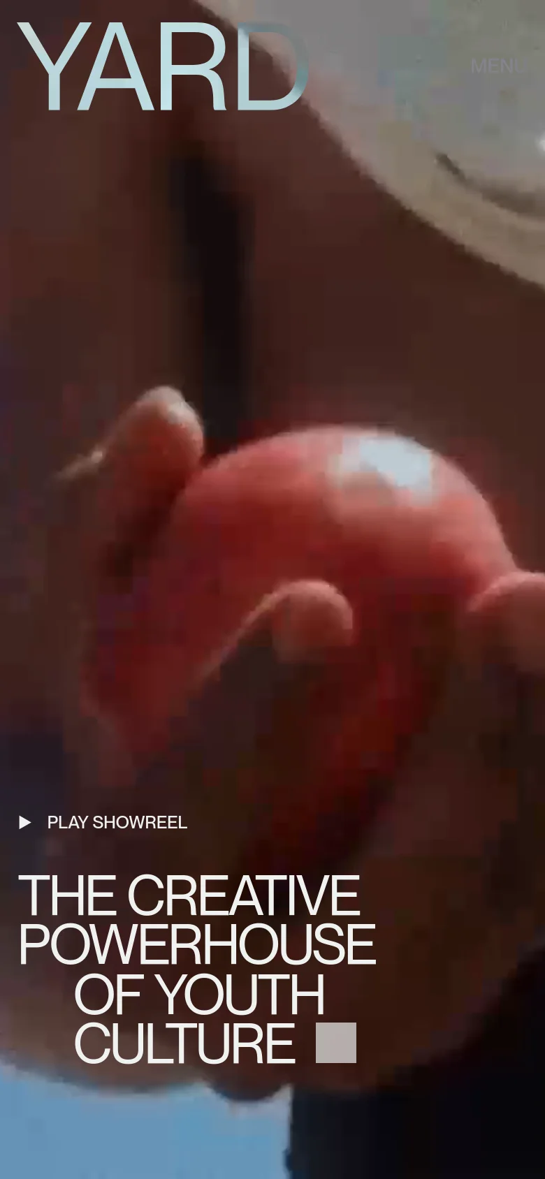 The mobile version presents a vertically oriented, close-up view of the cinematic background video. The YARD logo and a 'MENU' button are at the top, while the 'PLAY SHOWREEL' link and the main headline are stacked vertically in the lower half of the screen.