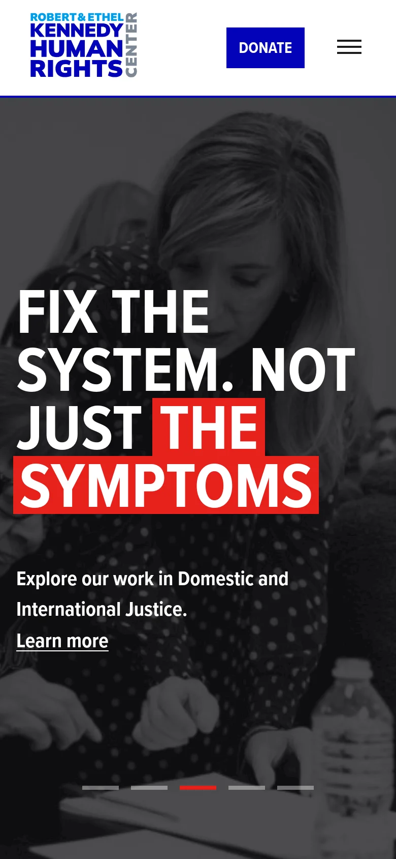 The mobile version presents a simplified header with the organization's logo, a blue Donate button, and a hamburger menu icon. The hero section features a large, grayscale background image with bold, white and red text overlays like 'FIX THE SYSTEM. NOT JUST THE SYMPTOMS' and a 'Learn more' link, optimized for a vertical screen.