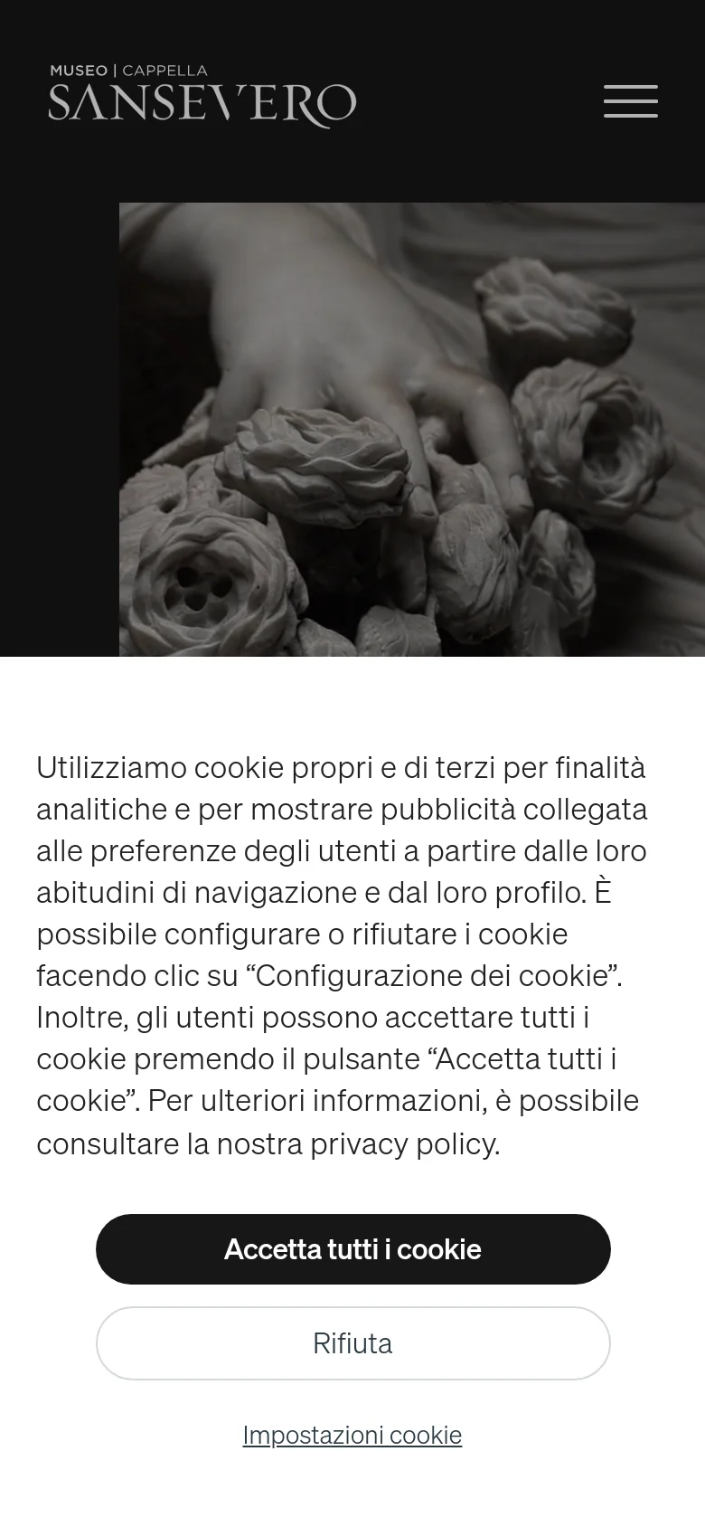 The mobile view maintains the dark aesthetic and centered logo, but the hero image is tightly cropped to the sculpture detail. The cookie consent overlay is more vertically oriented, occupying a significant portion of the mobile viewport with stacked buttons for 'Accetta tutti i cookie', 'Rifiuta', and 'Impostazioni cookie'.
