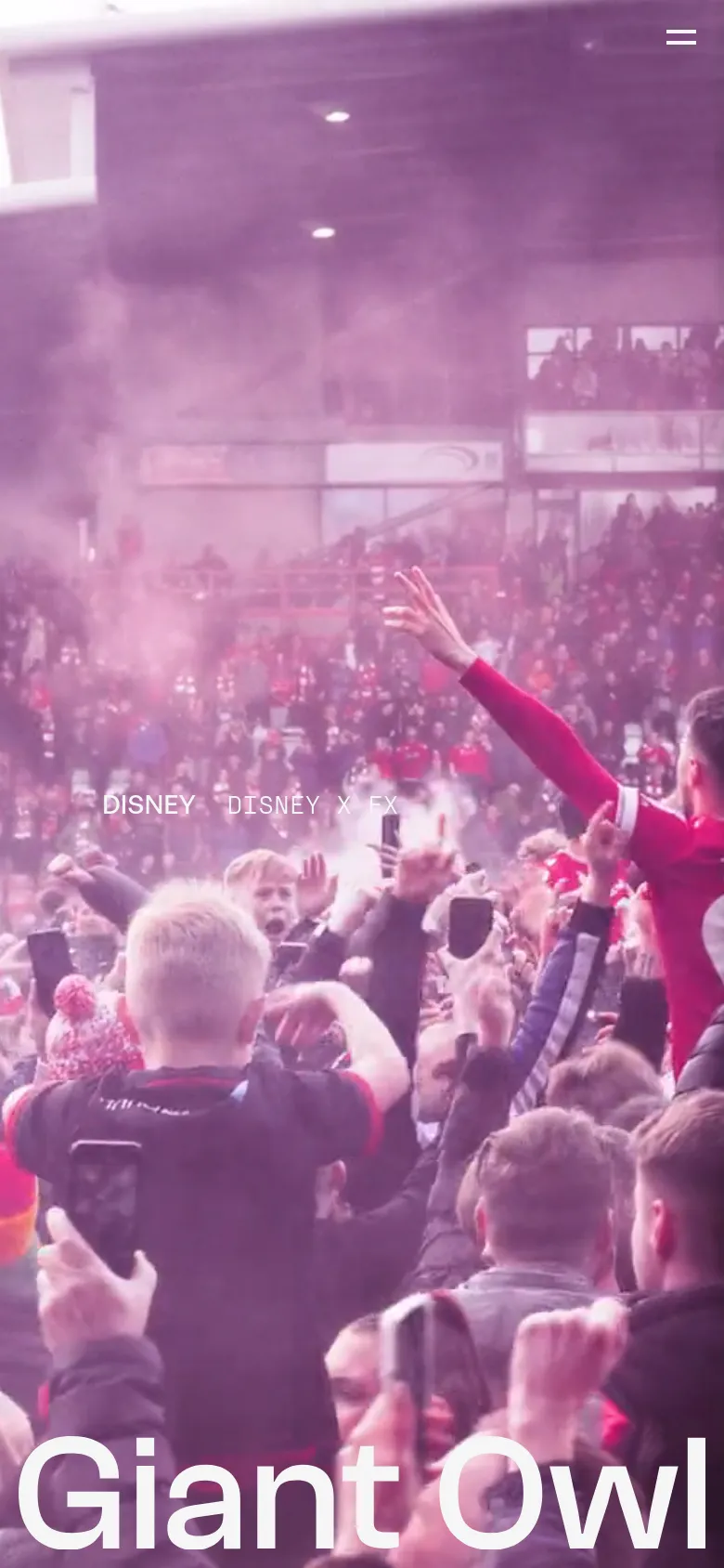 The mobile version displays a vertically oriented video background of a crowd in a stadium with a pinkish tint. The 'Giant Owl' logo is prominently positioned at the bottom in large white text, and the navigation is condensed into a hamburger menu icon in the top right corner.
