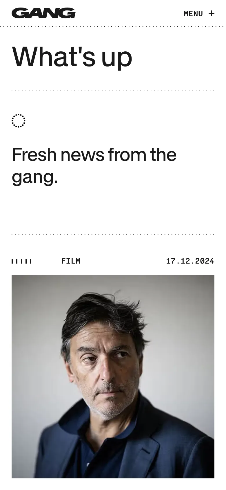 The mobile version presents a single-column vertical layout of the news feed, prioritizing large imagery and text for readability on small screens. The navigation menu is condensed into a 'MENU +' button at the top right, while the desktop's horizontal navigation bar is hidden. The 'What's up' headline and subheadline remain prominent at the top of the page.