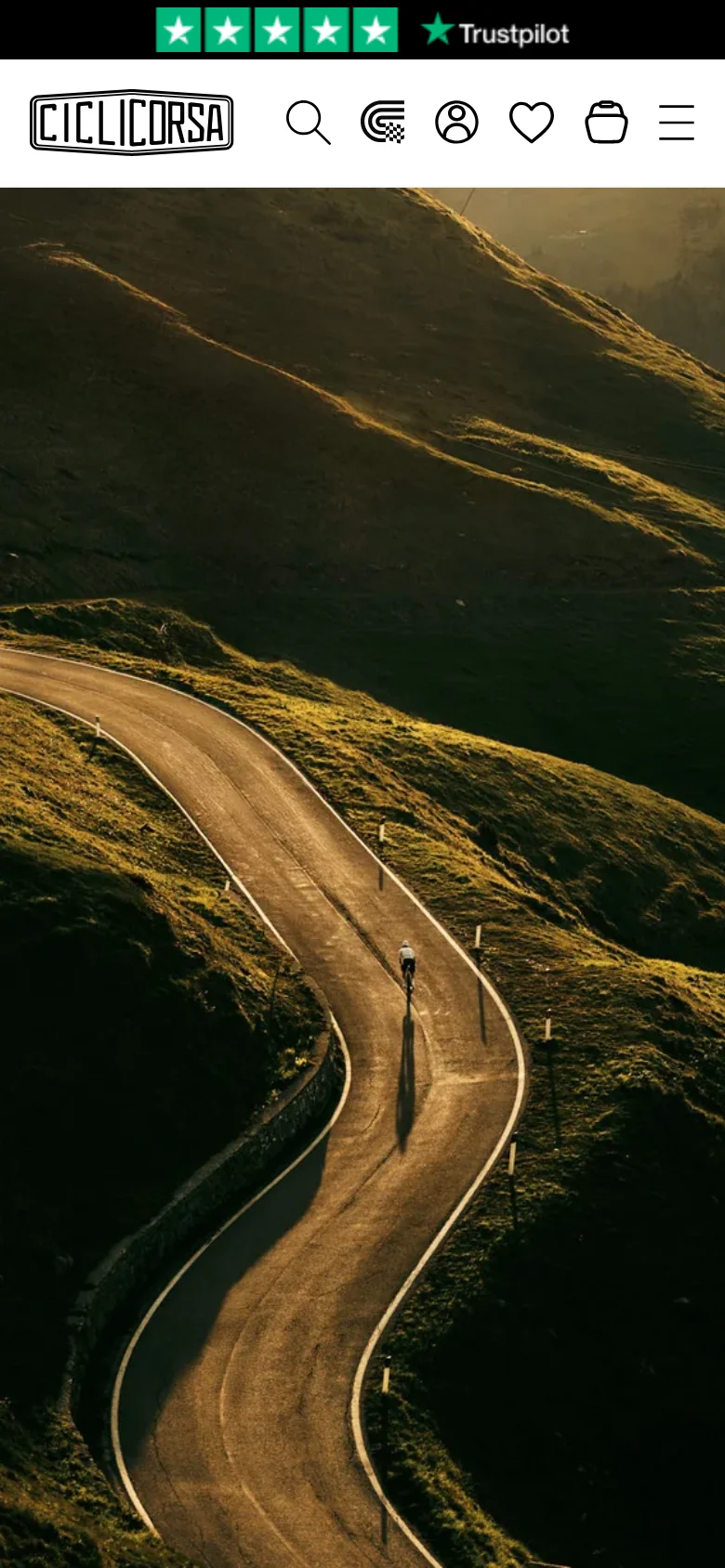 The mobile version displays a vertically oriented hero image of the winding mountain road, filling most of the initial viewport. The header is condensed into a logo, search icon, account, wishlist, and cart icons, with a hamburger menu icon on the far right. The text content follows below the image in a single-column stacked layout.