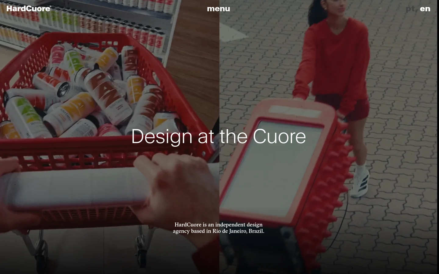 The desktop homepage features a split-screen hero image showing a red shopping basket filled with cans on the left and a person in red clothing on the right. Large white text reads 'Design at the Cuore' over the center, with a brief agency description below. The navigation includes the 'HardCuore' logo, a 'menu' button, and language toggles in the top corners.
