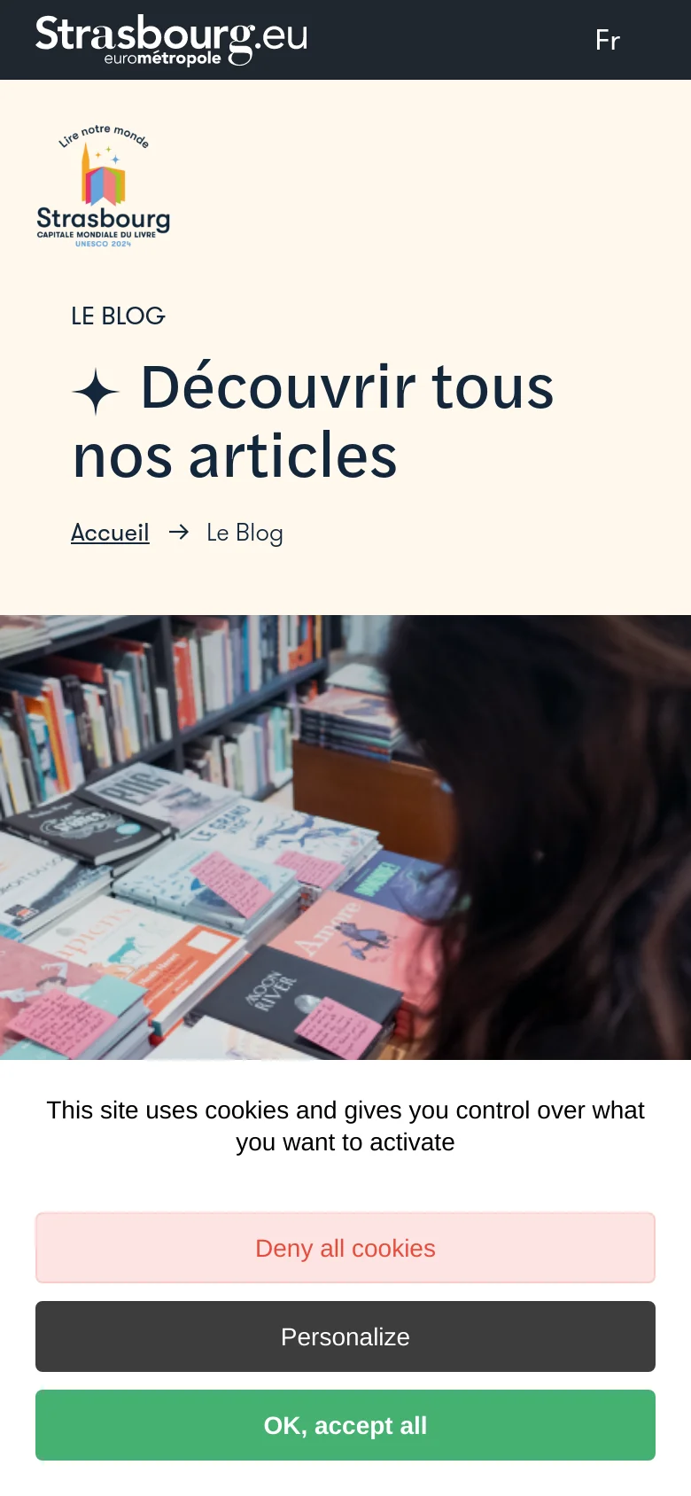 The mobile version uses a stacked layout where the cream-colored header section with the logo and large title sits above a full-width photograph of books. The navigation elements and 'Nous contacter' button from the desktop version are condensed or moved, and a large cookie consent banner occupies the bottom of the screen.