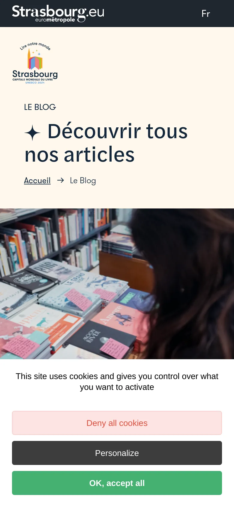 The mobile version uses a stacked layout where the cream-colored header section with the logo and large title sits above a full-width photograph of books. The navigation elements and 'Nous contacter' button from the desktop version are condensed or moved, and a large cookie consent banner occupies the bottom of the screen.