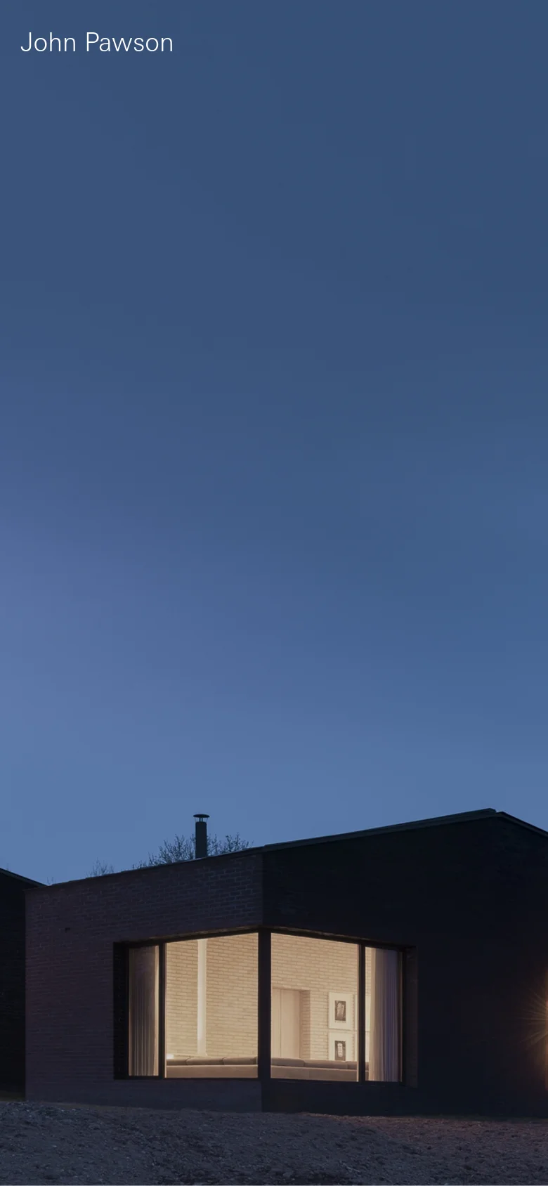 The mobile version maintains the minimalist aesthetic with a full-width vertical orientation of the architectural hero image. The text 'John Pawson' is positioned in the upper left, and the layout focuses on a single, large-scale view of the dark building under a twilight sky.